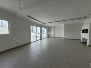 Interior de um espaço amplo com piso de cerâmica e grandes portas de vidro.