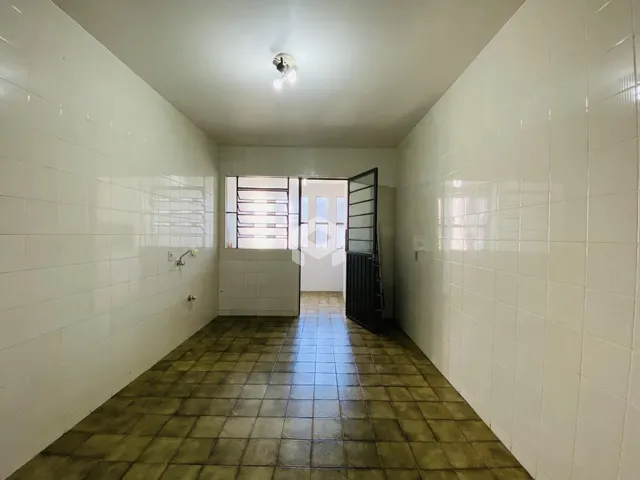 Corredor interno com piso de cerâmica e paredes brancas.