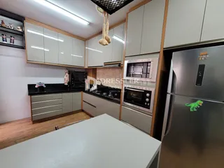A cozinha apresenta armários brancos e bancadas escuras com eletrodomésticos de aço inoxidável.