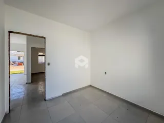 Um corredor com paredes brancas e piso de cerâmica.