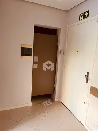 Hall de entrada com porta de madeira e parede branca em uma residência.