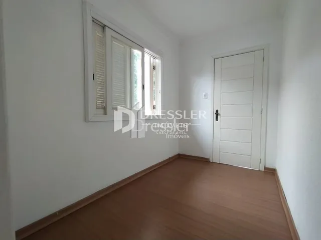 Interior de um cômodo com piso de madeira e janela.
