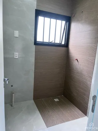 Foto interna de um banheiro com paredes de painel de madeira e piso claro.