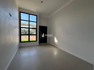 Interior de uma sala de estar com paredes brancas e piso claro.
