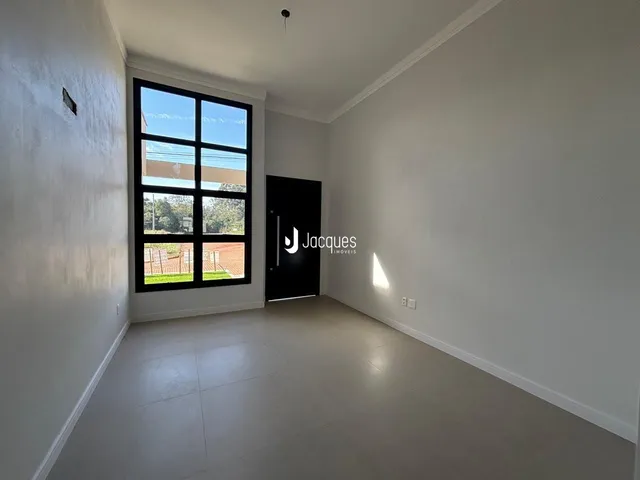 Interior de uma sala de estar com paredes brancas e piso claro.