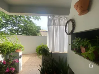 Vista externa com vegetação e parede branca.