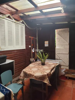 Interior de uma sala com teto de madeira e venezianas brancas.
