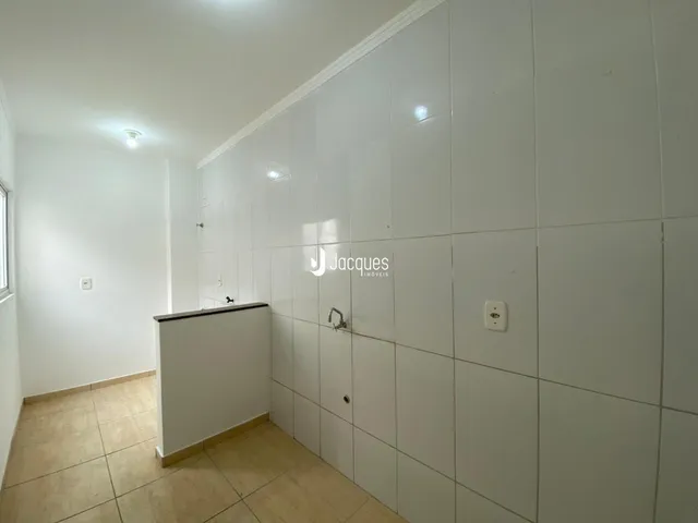 Vista de um corredor interno com paredes brancas e piso de cerâmica.