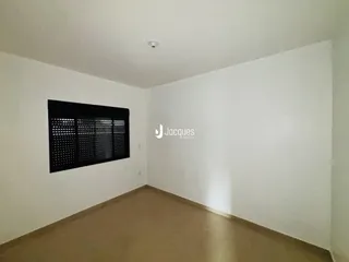 Ambiente interno de uma sala com paredes brancas e piso bege.