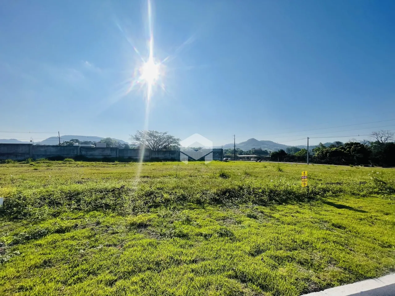 Vista de um campo gramado com colinas ao fundo.