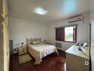 Quarto com cama, armário e piso de madeira em uma residência.