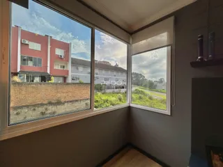 Vista externa de casas e vegetação através de grandes janelas de uma propriedade em Lajeado.