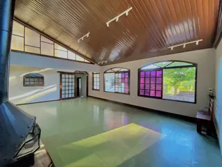 Esta é uma sala ampla com piso verde claro e grandes janelas que dão vista para o exterior.