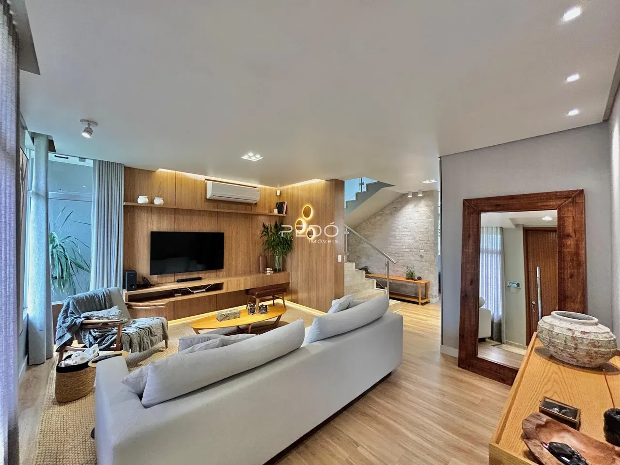 Sala de estar moderna com painéis de madeira e sofá claro.
