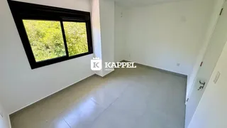 Foto de um ambiente interno com uma grande janela que oferece vista para a vegetação externa.