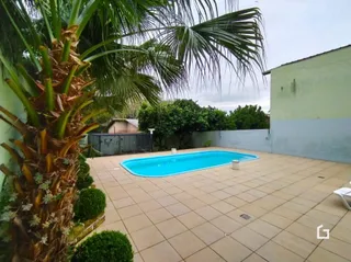 Piscina externa com área pavimentada e vegetação tropical.