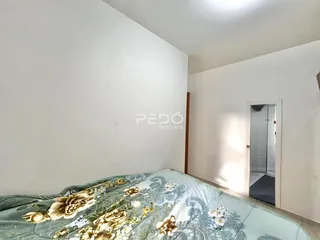 Quarto com cama decorada e parede branca.