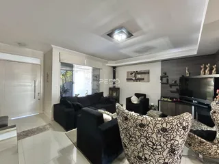 Sala de estar com sofá e poltronas escuras e piso de cerâmica clara.