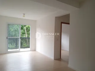 Interior de uma sala com piso de madeira e porta de vidro abrindo para o exterior.