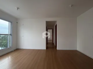 Vista interna de uma sala com piso de madeira clara e parede branca.