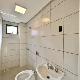 Foto de um banheiro com paredes revestidas por azulejos brancos.
