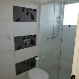 Foto de um banheiro com box de vidro e revestimento.