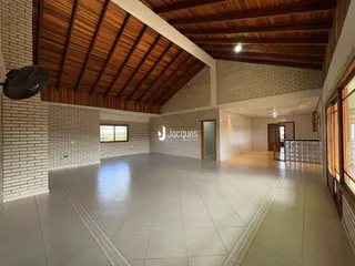 Ambiente interno amplo com teto de madeira e paredes de tijolo em uma residência.