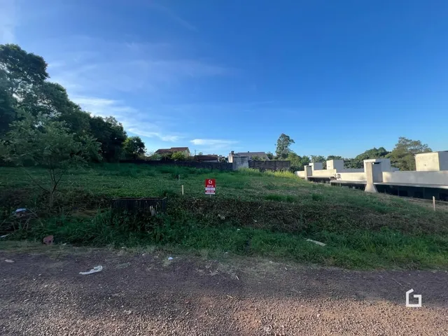 Vista externa de um terreno com vegetação e estruturas ao fundo.