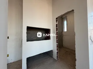 Foto de um ambiente interno com paredes de concreto aparente e estrutura em reforma.