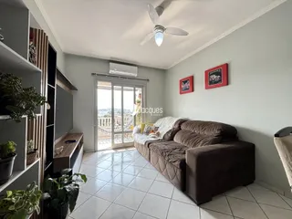 Sala de estar com sofá e porta de vidro abrindo para a varanda.