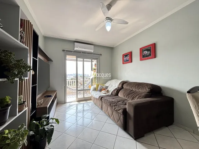 Sala de estar com sofá e porta de vidro abrindo para a varanda.