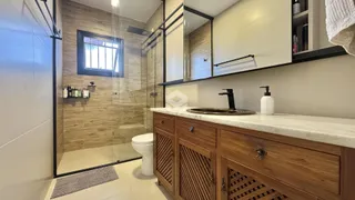 Banheiro moderno com box de vidro e bancada de madeira.