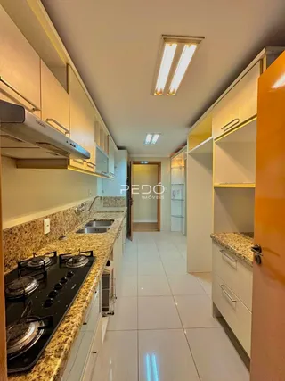 Foto da cozinha com armários brancos e piso claro.