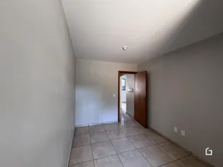 Vista de um corredor interno com paredes brancas e piso de cerâmica.