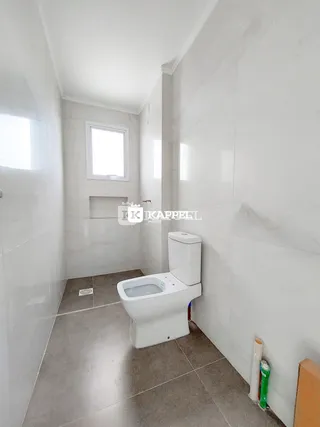 Banheiro com piso claro e revestimento branco.