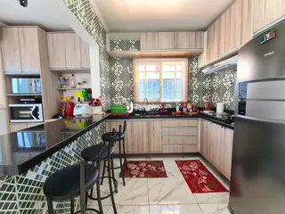 Cozinha moderna com armários de madeira e revestimento de azulejos verdes e brancos.