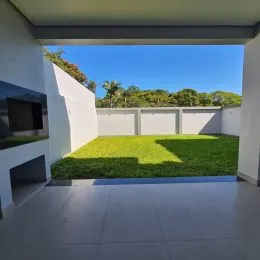 Vista de um gramado verde com árvores ao fundo.