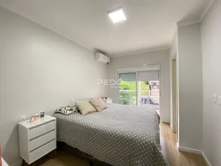 Quarto com cama e móveis brancos.