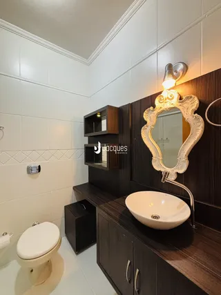 Banheiro com revestimento cerâmico e armários de madeira escura.
