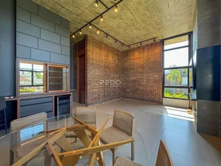 Ambiente interno com paredes de tijolo aparente e teto de concreto em uma sala de jantar.
