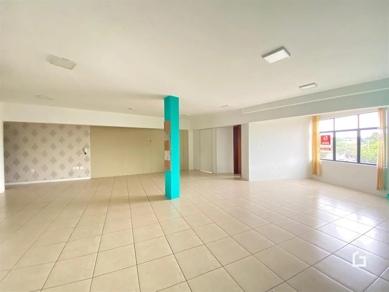 Ambiente interno amplo com piso de cerâmica clara em uma residência.