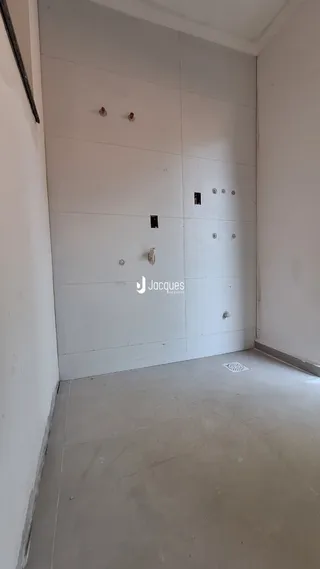 Parede interna branca com portas e piso de concreto.