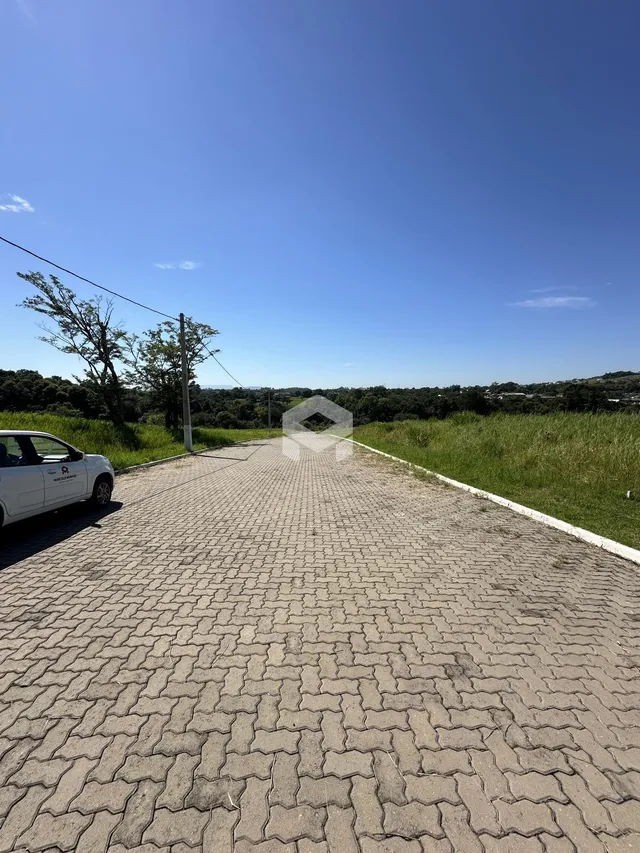 Vista da entrada de uma propriedade com paisagem verde ao fundo.