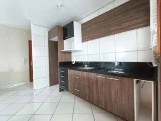 Uma cozinha moderna com armários de madeira e bancada escura.