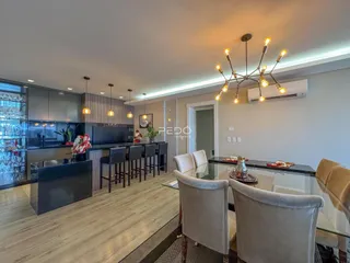 Ambiente moderno de sala de estar com cozinha integrada e área de jantar em um imóvel no Brasil.