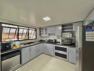 Cozinha moderna com armários brancos e bancadas escuras.