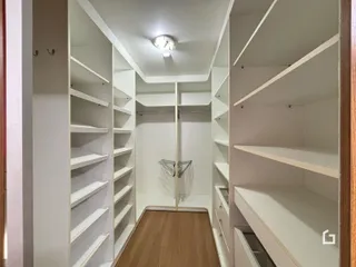 Hall de entrada com prateleiras brancas e piso de madeira clara.