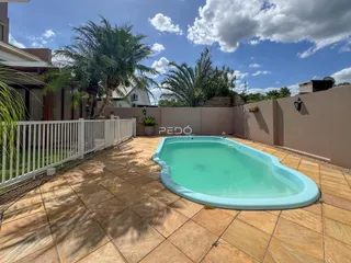 Piscina externa com deck e paisagismo no quintal.