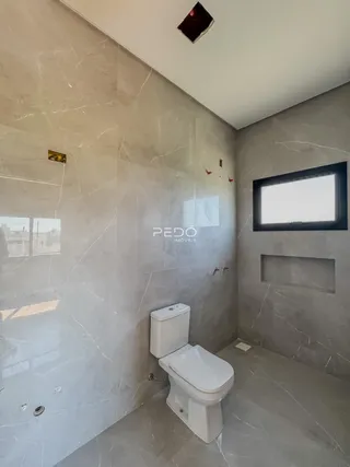 Foto de um banheiro com revestimento em mármore claro e vaso sanitário branco.