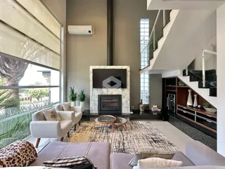 Sala de estar moderna com lareira e grandes janelas.